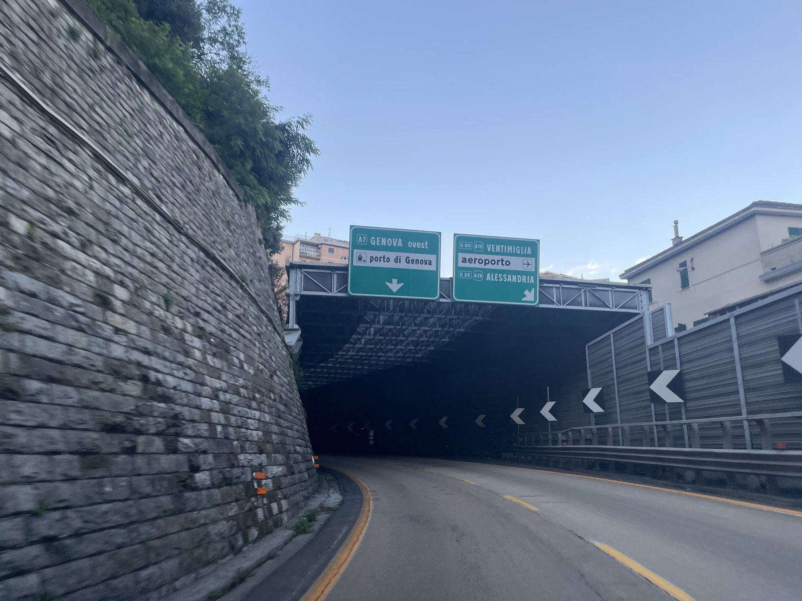 Entrada de un túnel en Génova con carteles verdes sobre la carretera: a la izquierda A7 Genova ovest y porto di Genova, a la derecha Ventimiglia, aeroporto y Alessandria