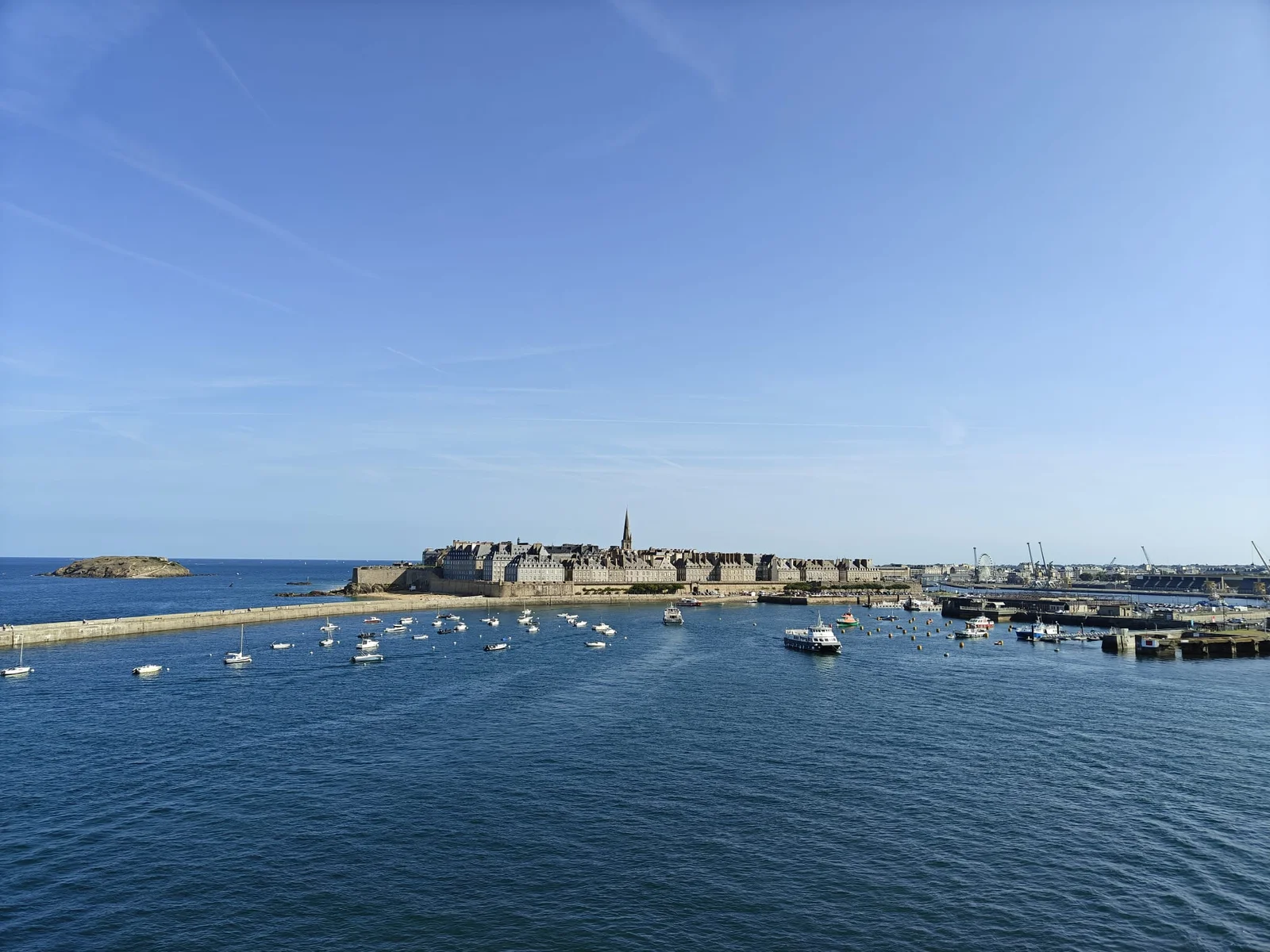 La ciudad amurallada de Saint-Malo y el campanario de la catedral, vistos desde la cubierta del ferry al salir, con decenas de barcos en el agua
